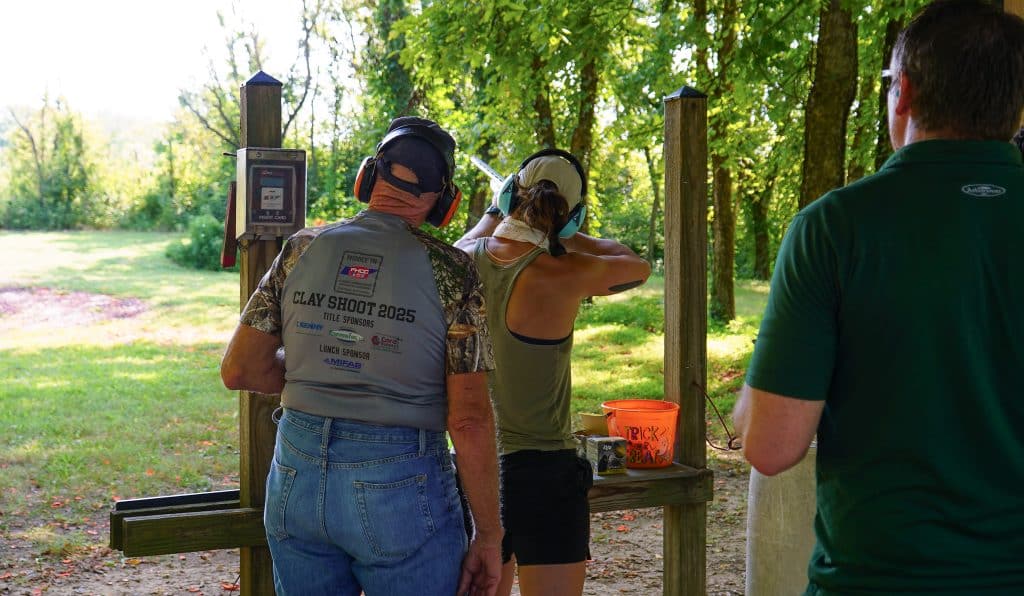 A woman getting ready to shoot clay as onlookers watch